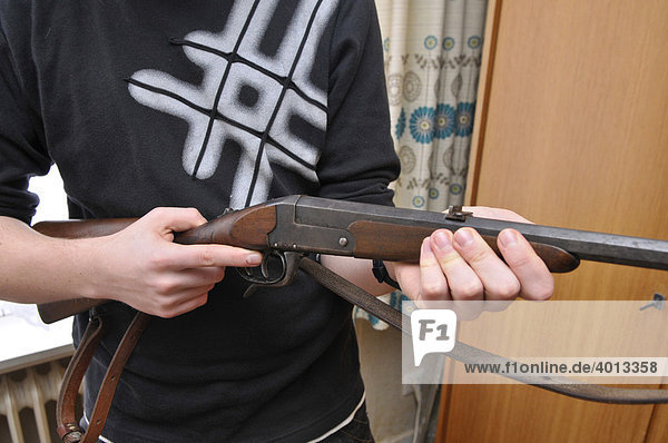 Teenager holding a sporting gun from his parents' weapon locker