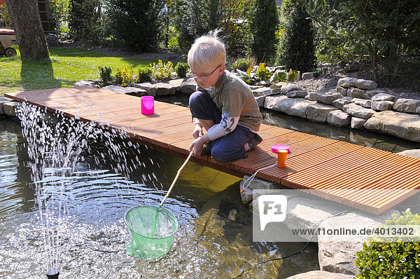 Small boy playing at a garden pond