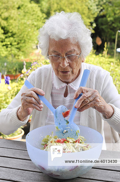 Seniorin bereitet einen Salat zu