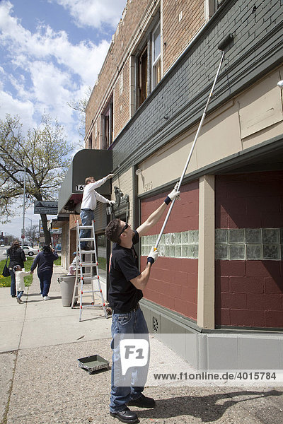 Freiwillige der U-SNAP-BAC Community Organisation streichen während eines Aktion zur Nachbarschafts-Säuberung ein Gebäude  Detroit  Michigan  USA
