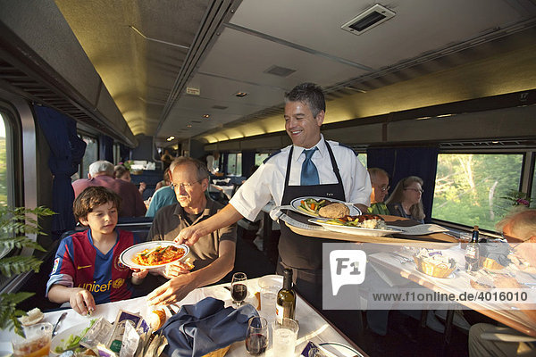 A waiter serves dinner in a dining car on a transcontinental Amtrak train  Aboard the California Zephyr  Iowa  USA