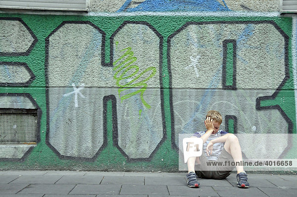 Frustrierter neunjähriger Junge vor einer Graffitiwand  Deutschland  Europa