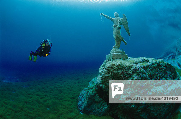 Scuba diver in a mountain lake with a statue of an angel