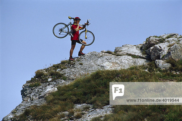 Radfahrer trägt sein Mountainbike auf dem Weg zum Berggipfel des Schiefersteines,  Reichraming,  Oberösterreich,  Österreich,  Europa
