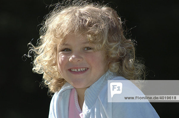 Lachendes Mädchen,  5 Jahre,  mit blondem Haar im Gegenlicht,  Portrait