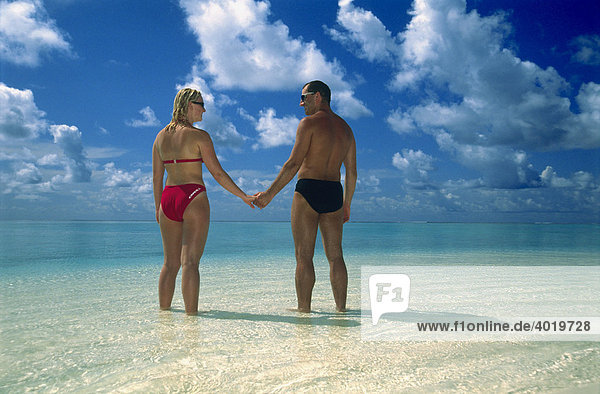 A couple standing in the ocean shallows  Summer Island Village  North Male Atoll  Maldives  Indian Ocean