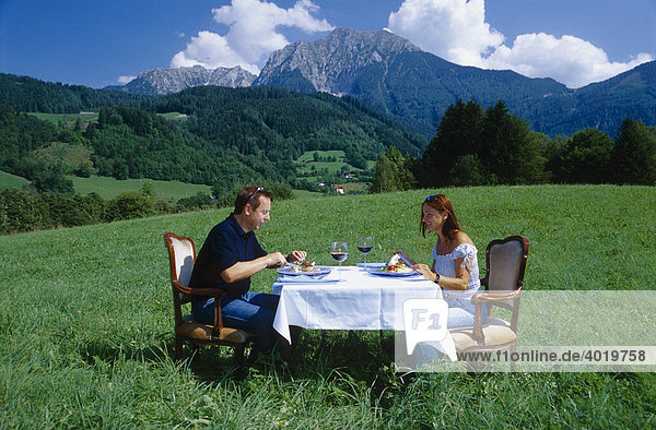 Frau und Mann sitzen an gedecktem Tisch auf der Wiese  dahinter der Große Phürgas  Oberösterreich  Österreich  Europa