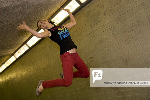 Confident female teenager jumping with excitement in an urban underpass