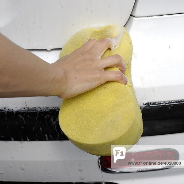 Woman using a sponge while cleaning her car