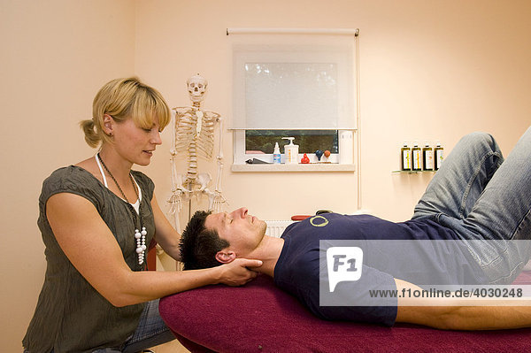 Physiotherapeutin  Lehrerin für Alexandertechnik führt mit einem Patienten eine Entspannungsübung für den Hals-Nacken-Bereich im Praxisraum durch