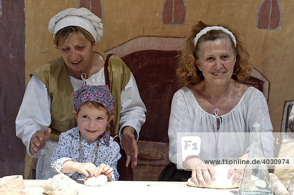 Frauen mit Kind beim Fladenbrotbacken  historisches mittelalterliches Stadt Spiel  Besetzung Canellis  L´assedio di Canelli  Canelli  Provinz Asti  Piemont  Italien