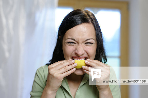 Junge Frau lutscht an einer Zitrone  Vitamin C  Sauer macht lustig