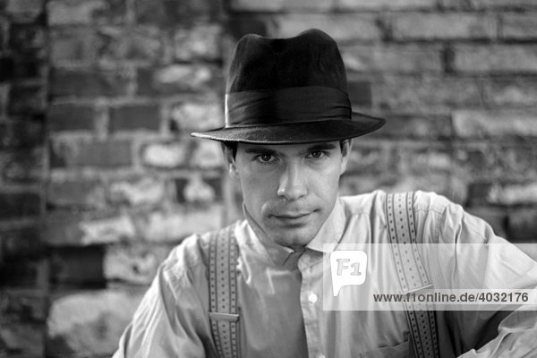 Schwarz-weiß Portrait eines jungen Mannes im Stil der 20er Jahre mit Hut  Hemd  Hosenträgern