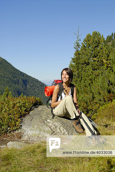 Junge Frau rastet beim Wandern in den Bergen  Trekking  Wald  Stubaital  Tirol  Österreich  Europa