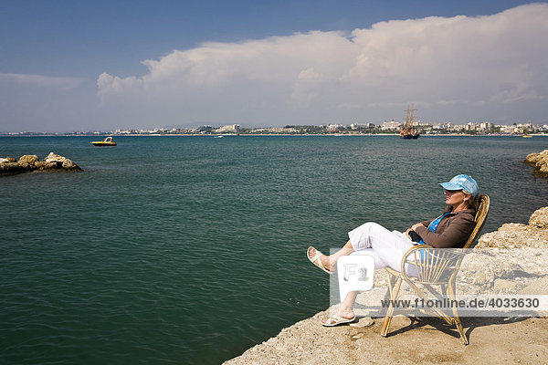 Frau sitzt auf einem Stuhl im Hafen von Side  Türkische Riviera  Türkei  Asien