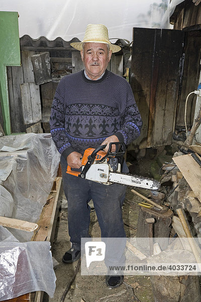 Romanian man with a hat and a chainsaw  Bezded  Salaj  Transylvania  Romania  Europe