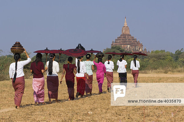 Junge Burmesinnen mit Sonnenschirm überqueren ein Feld bei der Sulamani Pagode  Bagan  Myanmar  Burma  Birma