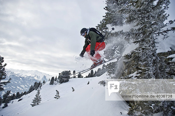 Tiefschnee Skifahrer  Freerider  springt über Felsen  mit Zillertaler Alpen  Tirol  Österreich  Europa