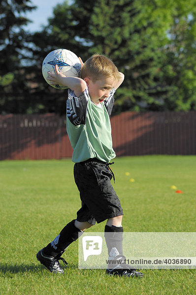 Young boy  age 6  taking a throw-in for his team at an under 8 soccer game