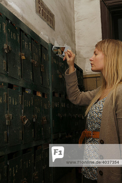 Blonde woman  mid-twenties  putting something into a letterbox  China  Asia