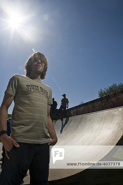 Young man standing in front a skateboard ramp