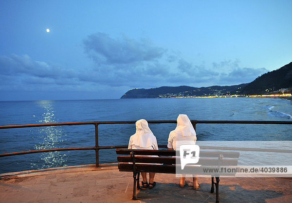 Zwei Nonnen sitzen abends auf Bank und betrachten das Meer am Ufer von Alassio  Riviera dei Fiori  Ligurien  Italien  Europa