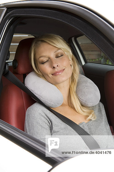 Blond woman with a neck cushion sitting in a car
