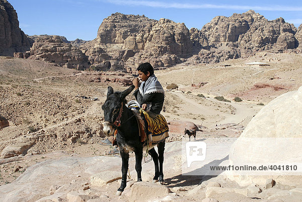 Bedouin boy riding a donkey or ass (Equus asinus)  Petra  Jordan  Middle East  Asia