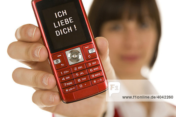 Twenty-year-old woman holding a mobile phone into the camera  with a message on the display  Ich Liebe Dich  I love you