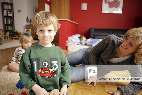 Blonde Mutter mit 3 kleinen Kindern im Wohnzimmer