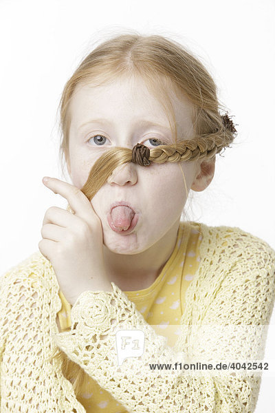 8-jähriges Mädchen macht Grimasse  Haarzopf im Gesicht