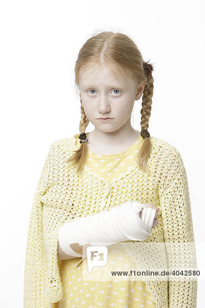 8-jähriges Mädchen mit Haarzöpfen und gebrochenem Arm in Gips  traurig