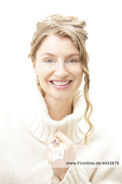 Blonde Frau mit lockigen Haaren im weißen Rollkragen-Pullover  lacht