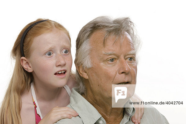 8-year-old red-haired girl hugging her grandfather  both with shocked expressions