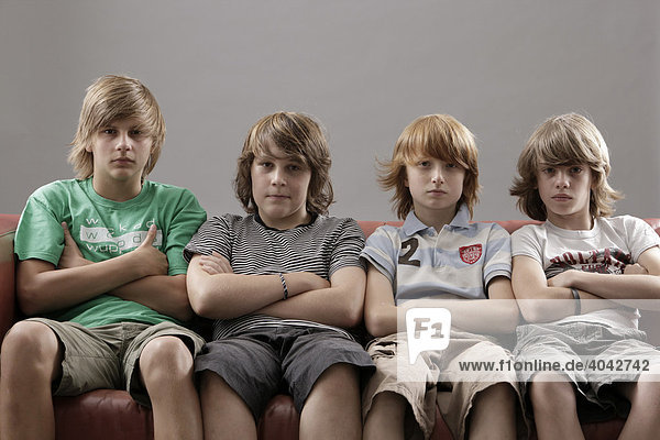 4 Jungen mit verschränkten Armen auf einem Sofa