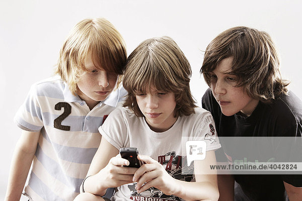 Drei Jungen spielen mit Handy