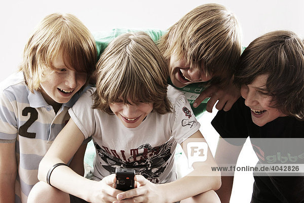Vier Jungen spielen mit Handy