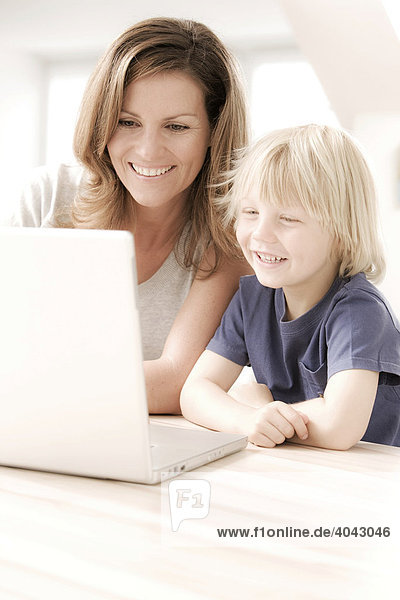Blonde son and mother using a laptop  laughing