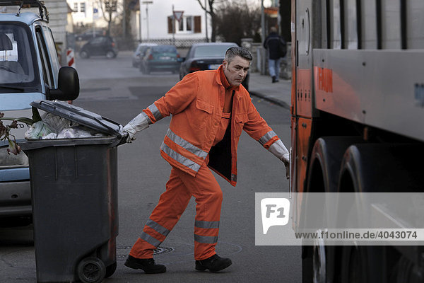 Garbage collector for the Stuttgart garbage company  called AWS or Abfallwirtschaft Stuttgart  pulling a garbage container behind the garbage truck  Stuttgart Weilimdorf  Baden-Wuerttemberg  Germany  Europe