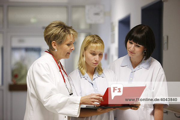Female doctor talking to two nurses in a hospital ward corridor
