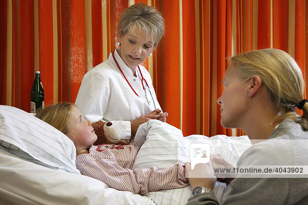 Ärztin spricht mit einer jungen Patientin  7 Jahre  und ihrer Mutter am Krankenbett in einem Krankenhaus