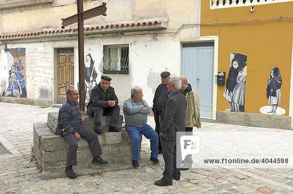 Alte Männer sitzen an einem Kreuz  dahinter Murales  politische Wandmalerei  Orgosolo  Sardinien  Italien  Europa