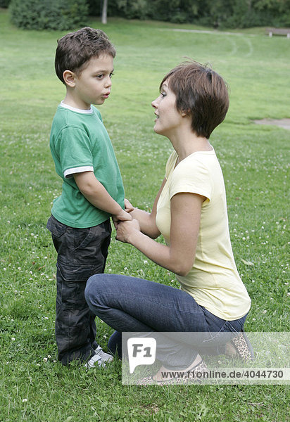 Junge Mutter redet mit Sohn  Kind im Park