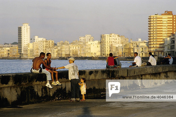 Abendstimmung am MalecÛn  junge Leute sitzen auf der Küstenmauer  Sykyline von Centro Habana  Havanna  Kuba  Karibik