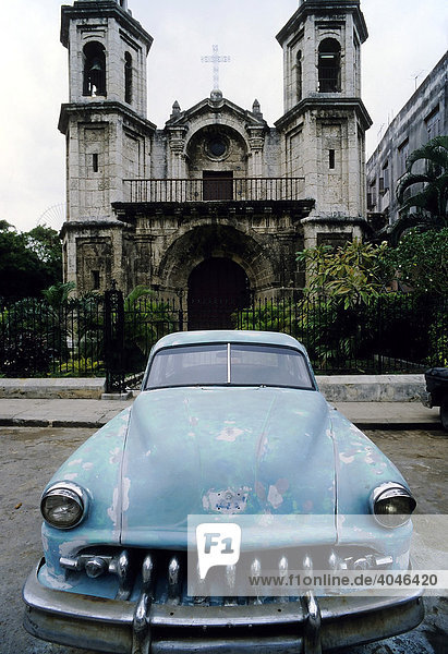 US-Oldtimer vor einer Kirche  Haifischmaul-Kühler  überlackierte Roststellen  La Habana Vieja  Havanna  Kuba  Karibik