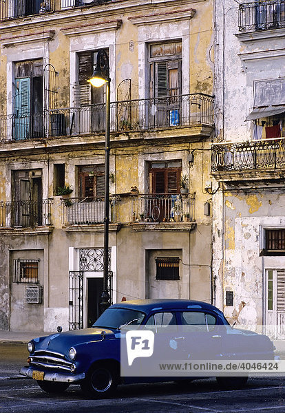 US-Oldtimer parkt unter einer Straßenlampe vor Häusern mit bröckelnder Fassade  Abendstimmung  La Habana Vieja  Havanna  Kuba  Karibik