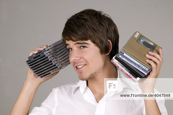 Young man holding CDs to his ears