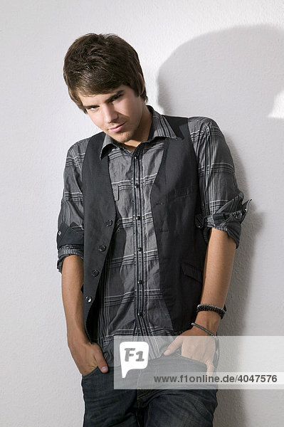 Young man standing confidently in front of a wall