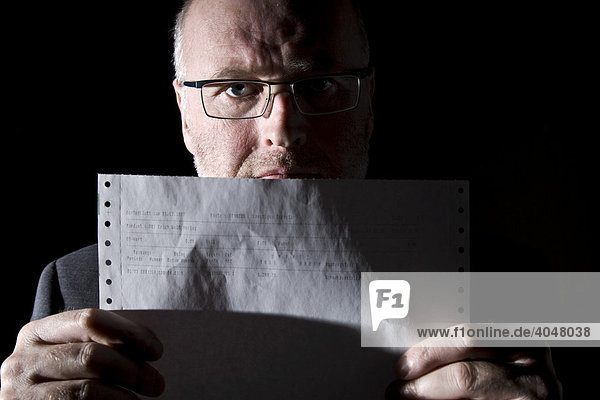 Businessman studying a strip of perforated computer paper  stock quotes