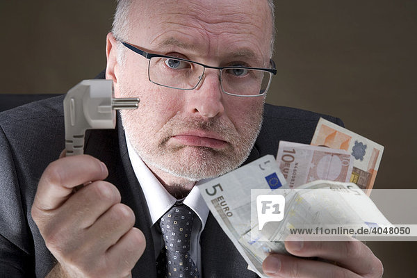 Man holding an electric plug and banknotes  expensive electricity